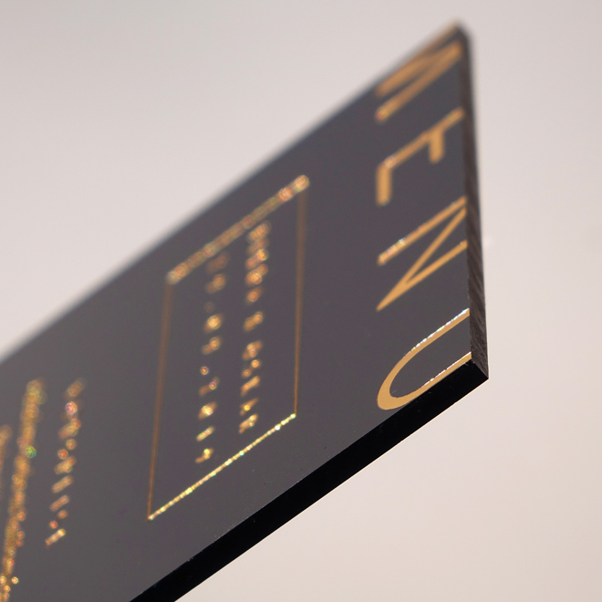 Dicke schwarze Einladungskarte mit goldenerm Text.